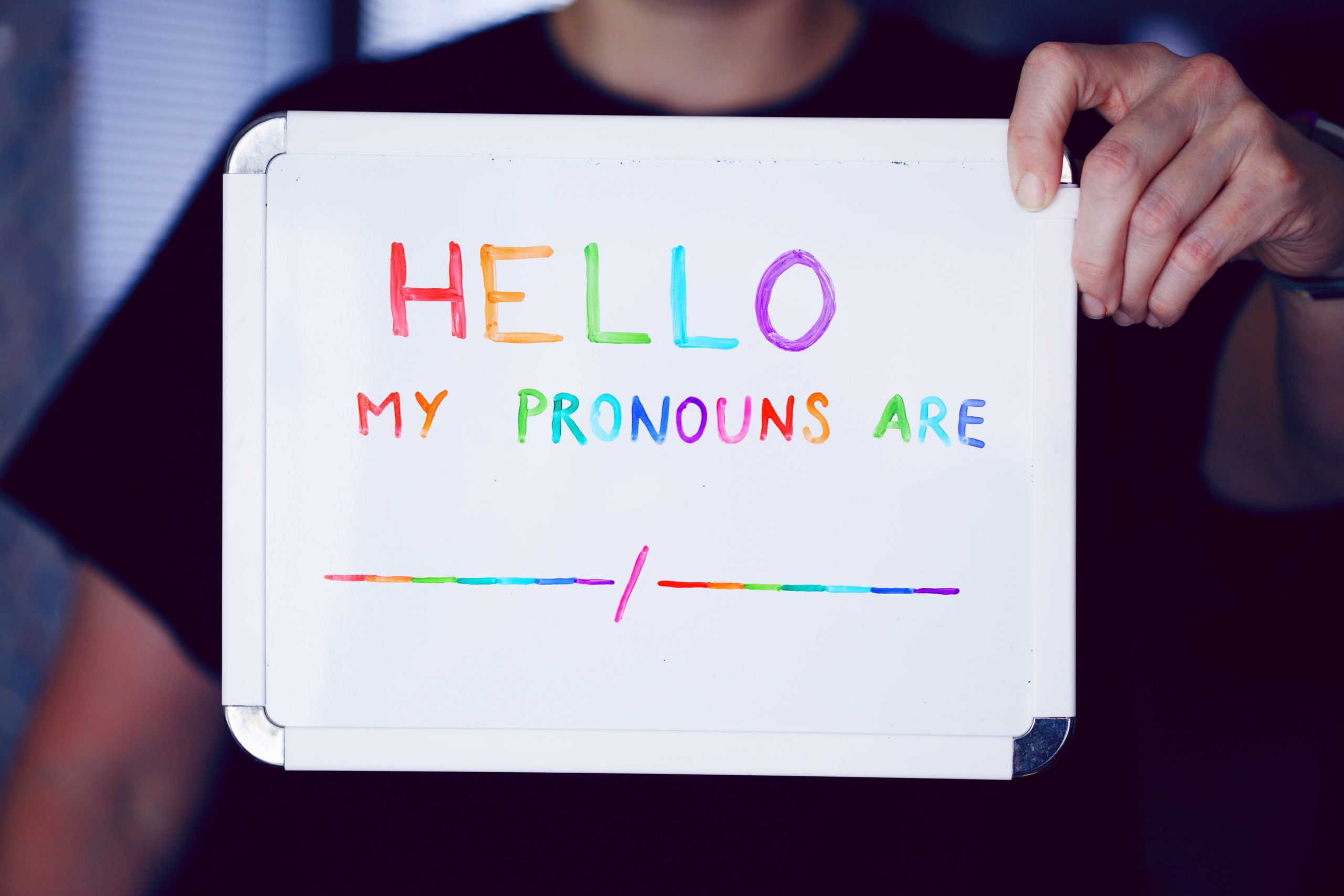 person holding sign that says "Hello my pronouns are"